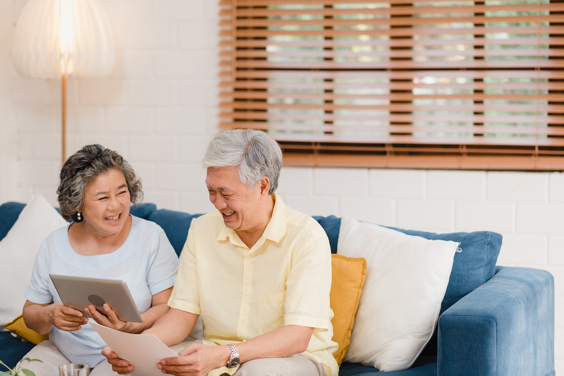 Asian elderly couple using tablet watching TV in living room at